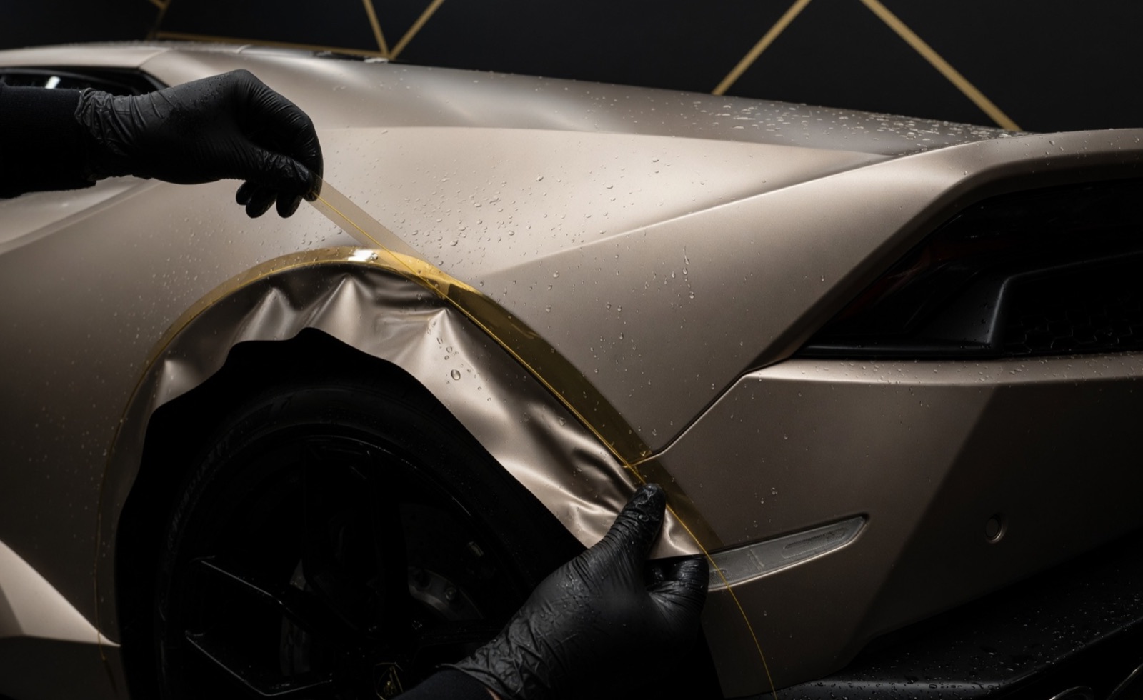 Technician applying gold vinyl wrap film to a car's front fender at Innovative Car Clinic, Ancaster, Ontario